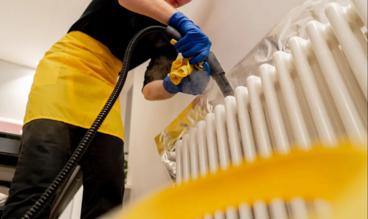 A cleaner steam cleaning a radiator during a deep clean