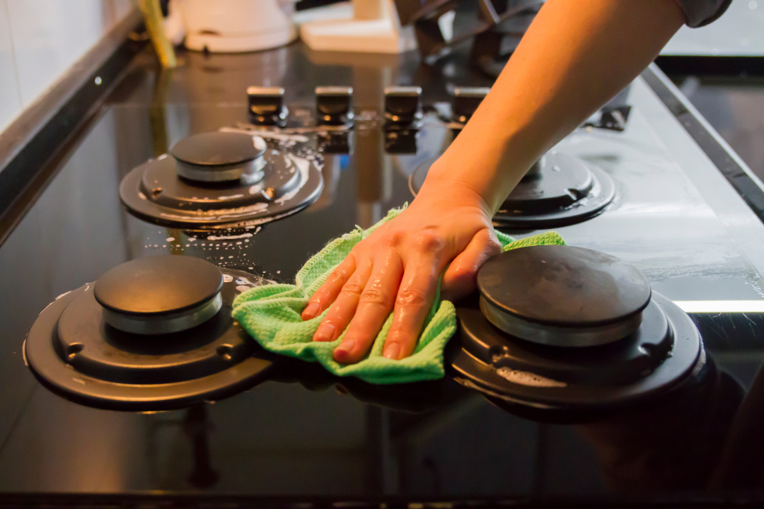 Scrubbing a stovetop during a detailed kitchen deep clean
